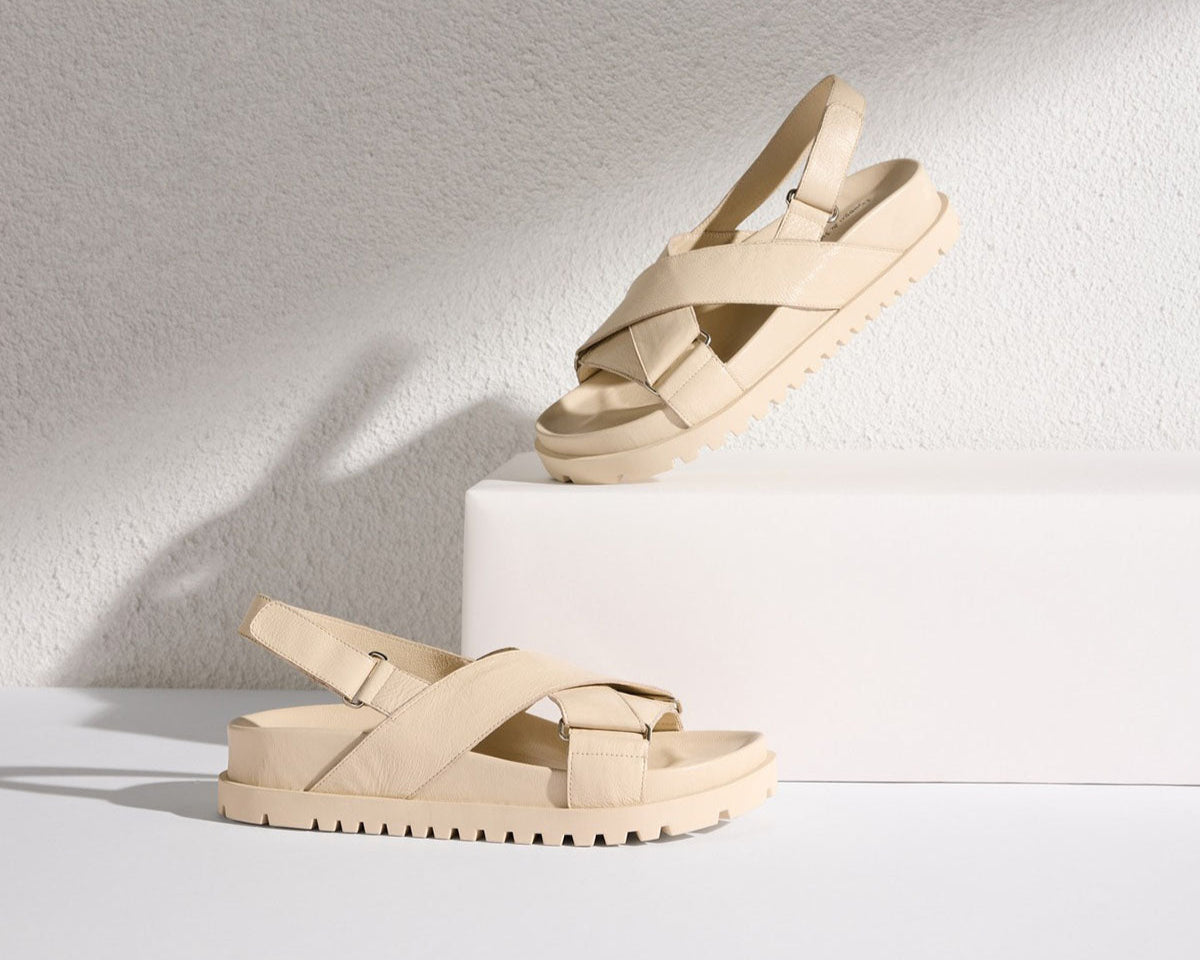 Beige sandals on a white surface with a light gray background